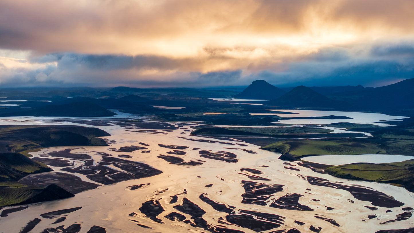 Landmannalaugar. Aerial view of a river delta with a dramatic sky over a mountainous landscape.