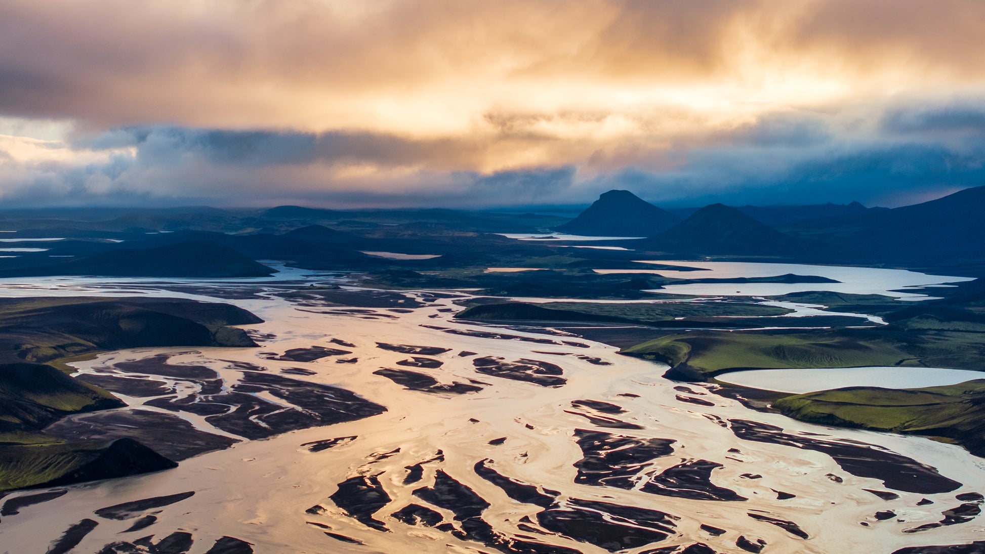 Landmannalaugar. Aerial view of a river delta with a dramatic sky over a mountainous landscape.