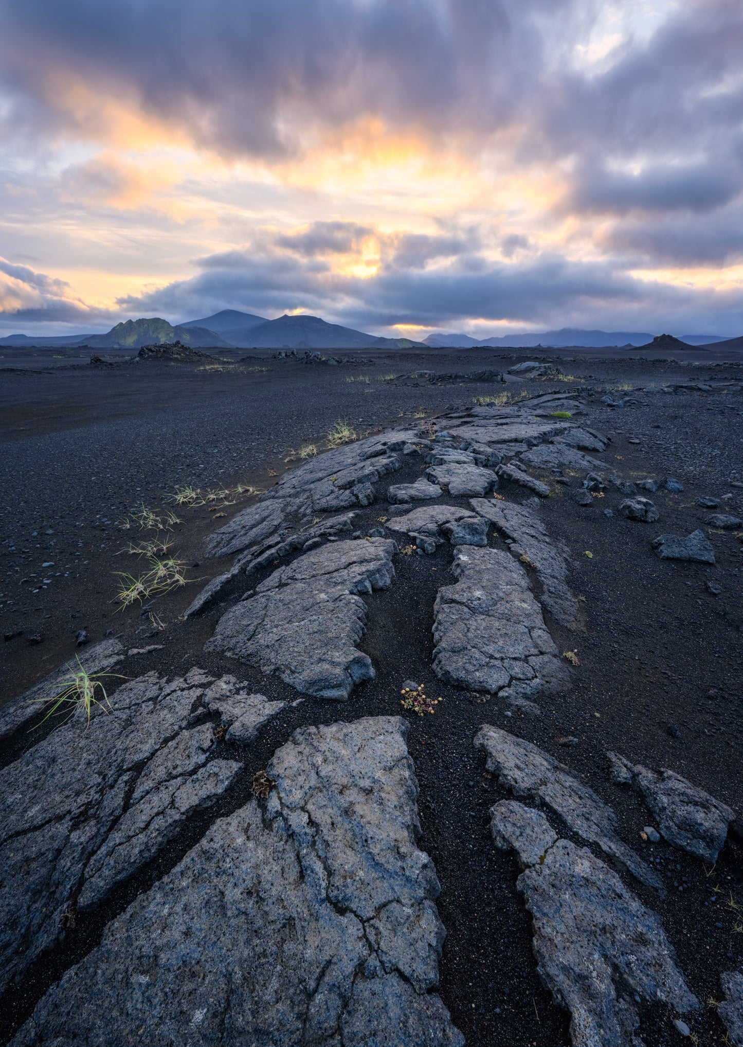 Landmannalaugar. Lava rock formation with a dramatic sky over a mountain range