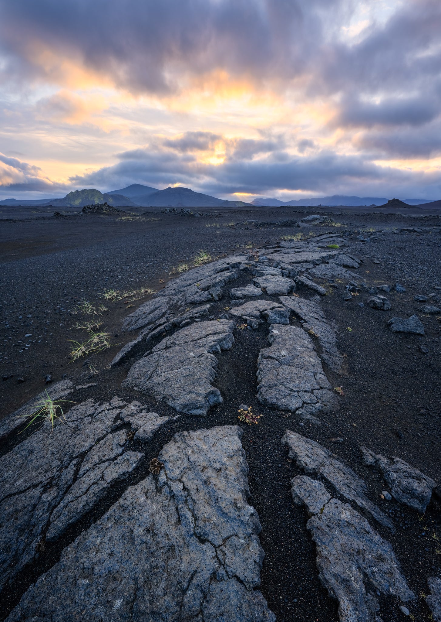 Landmannalaugar. Lava rock formation with a dramatic sky over a mountain range