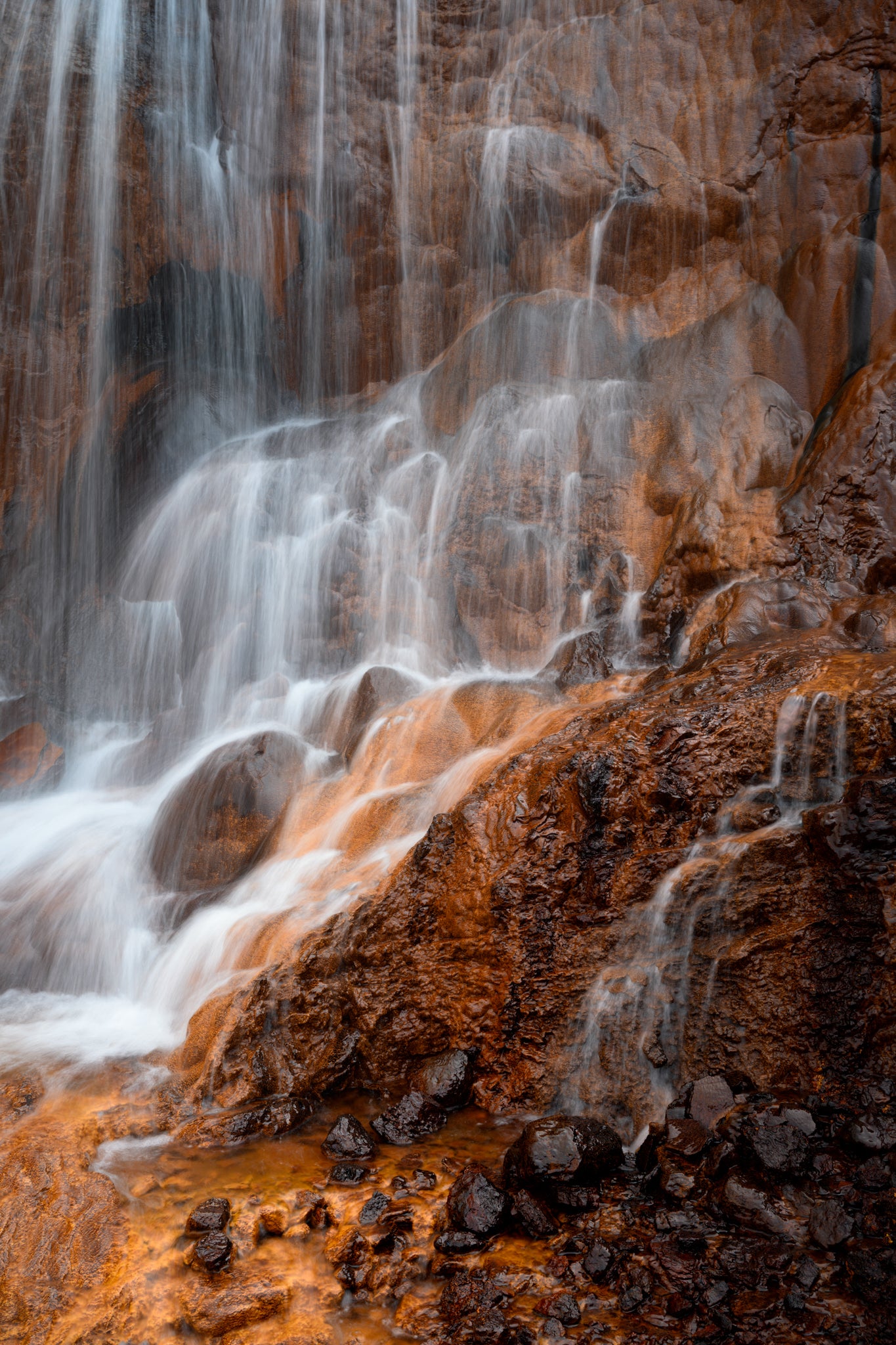 Raudarfoss Waterfall cascading over rocky terrain with a warm color palette.