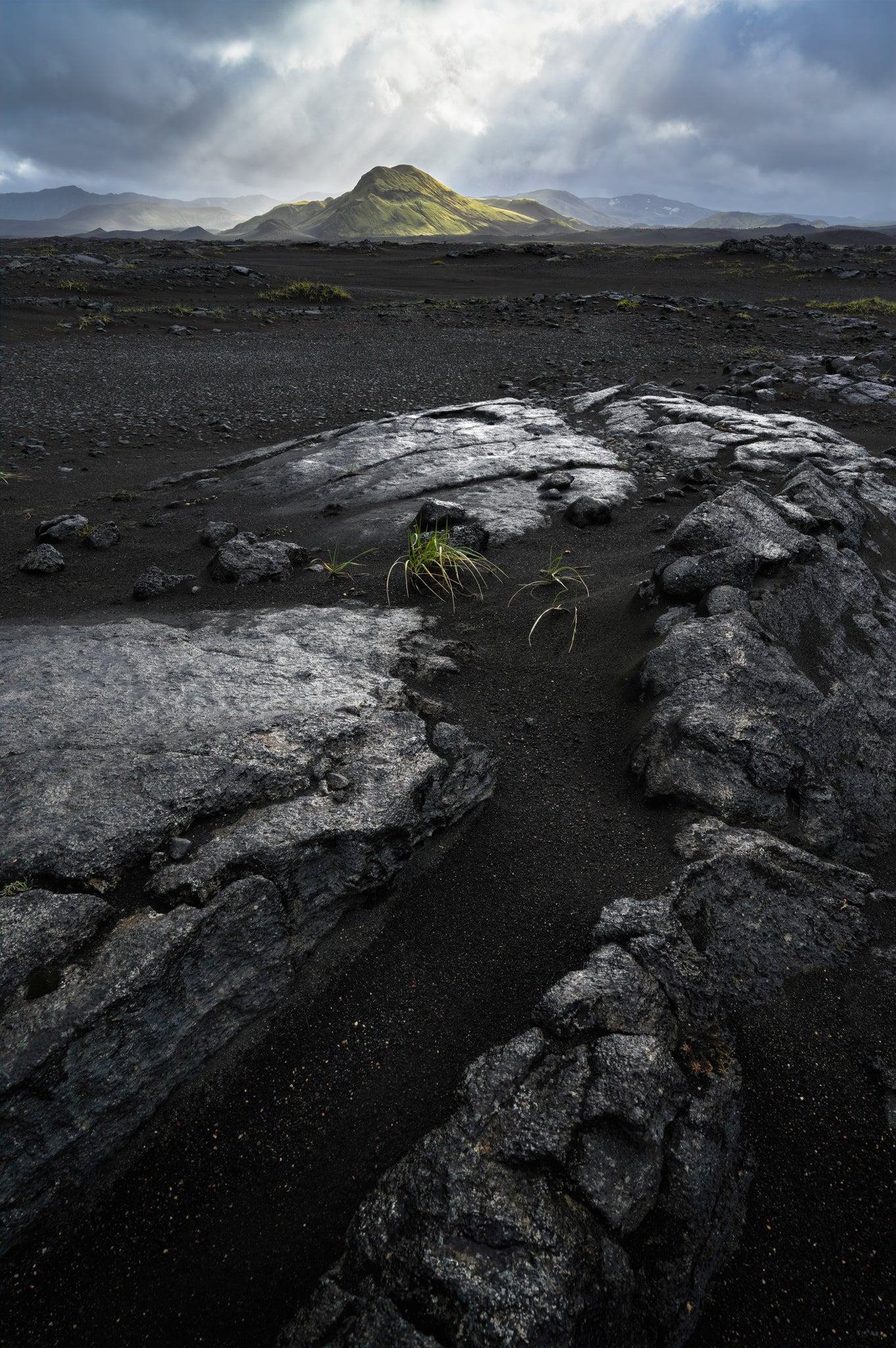 Iceland Highland volcanic black sands. Stony landscape with a mountain under a cloudy sky