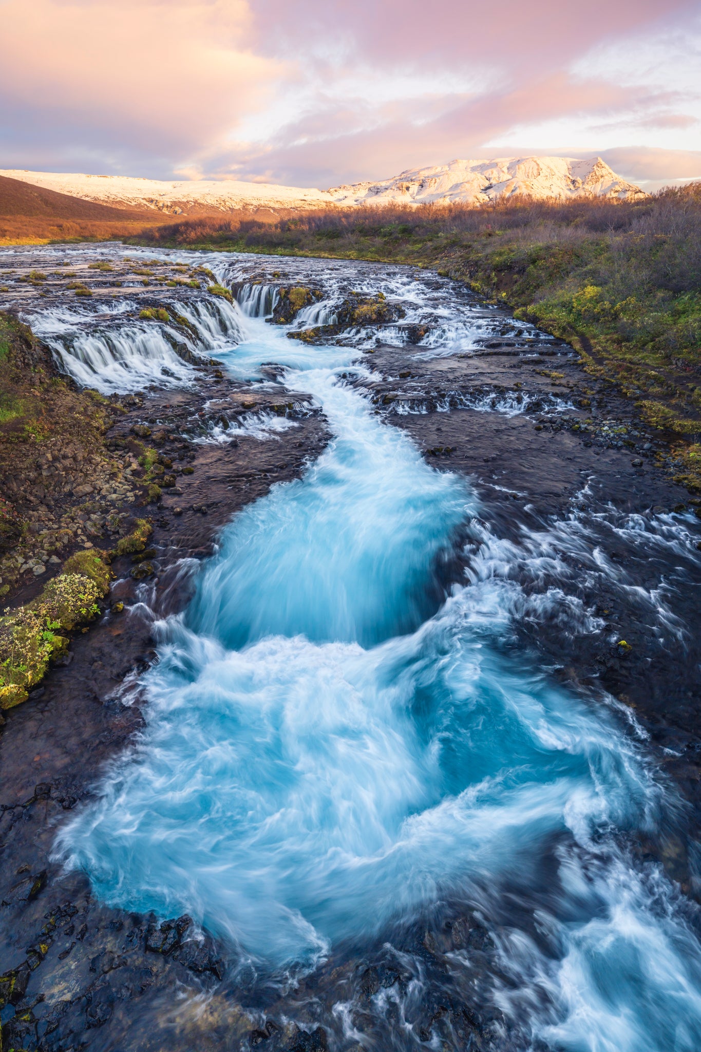 Bruafoss. Powerful waterfall in a natural landscape with mountains in the background