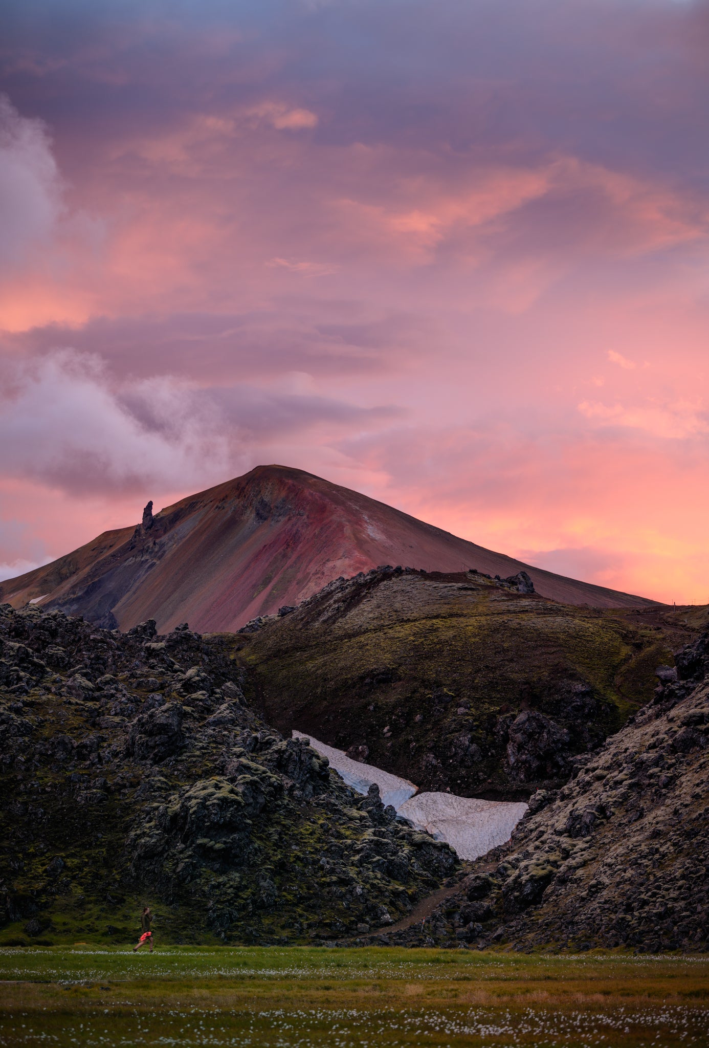 Landmannalaugar. Person standing on a hill with a dramatic sky at sunset
