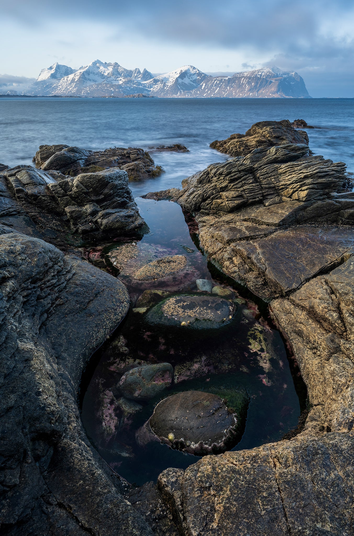 Rocks with water and snow-capped mountains in the background