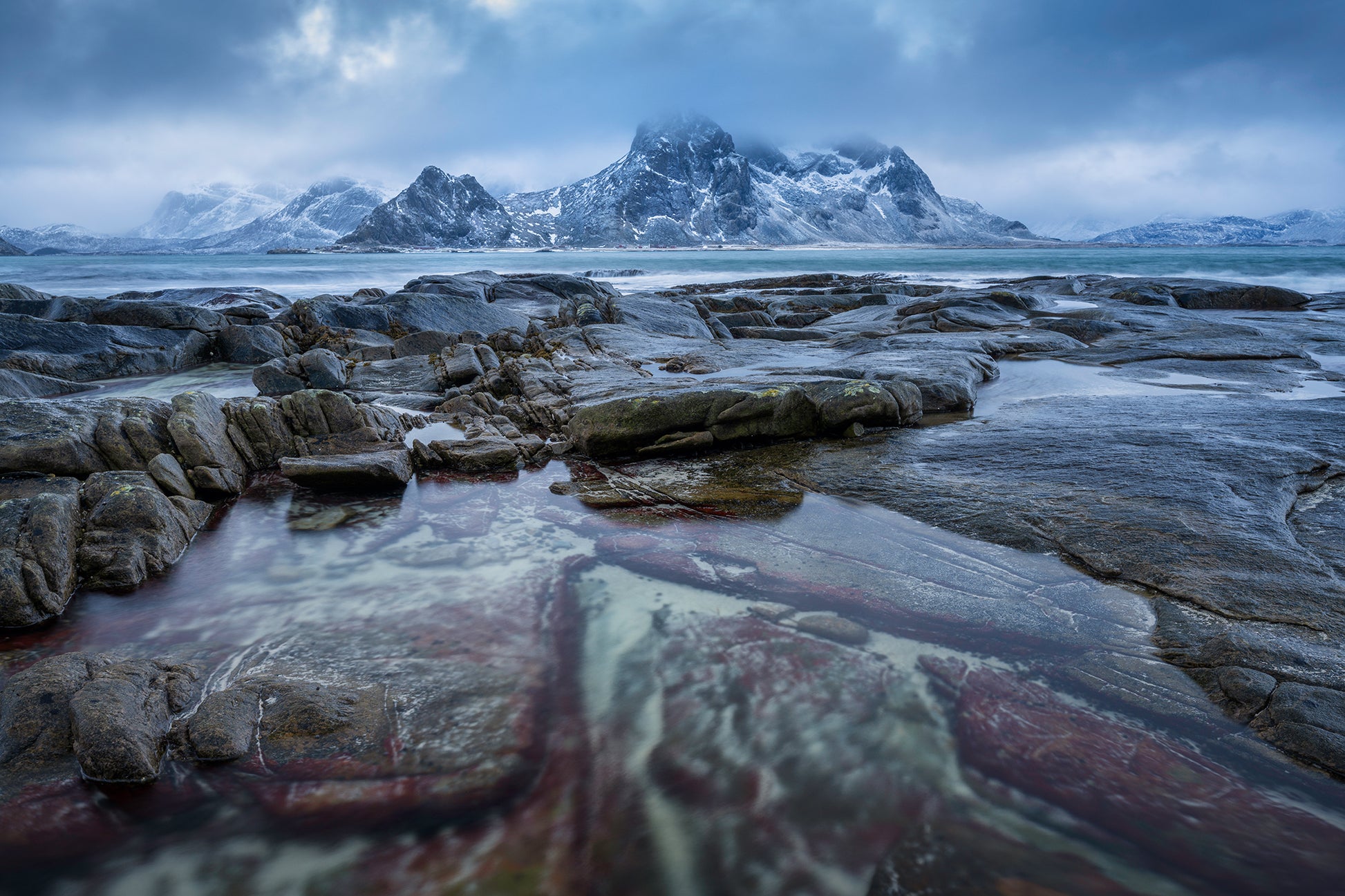 Vareid. Stormy moody sunset in arctic conditions with red stained granite in coastal scene