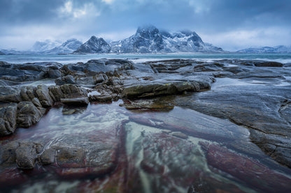Vareid. Stormy moody sunset in arctic conditions with red stained granite in coastal scene